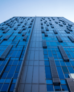 Low-angle photo of a glass office skyscraper against a clear sky