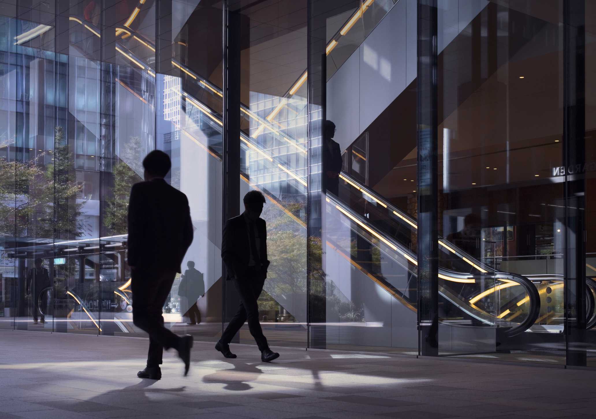Morning image with office workers passing modern office facade in Tokyo, Japan.