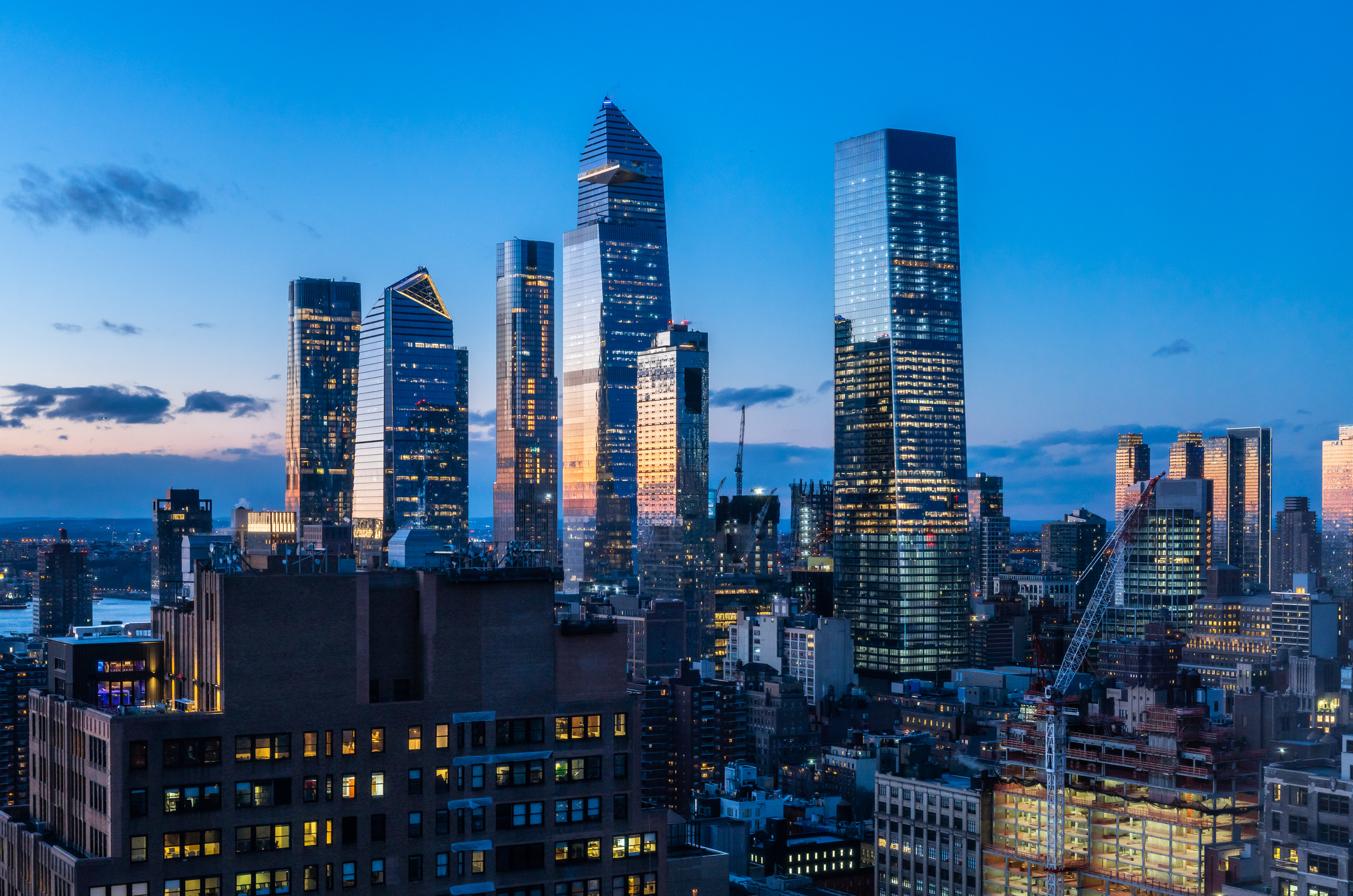 This high angle night view from the Chelsea neighborhood in New York looks west toward the far west side of Manhattan. Some of the prominent buildings seen here are Hudson Yards and Manhattan West, both multi building developments for commercial, residential and retail occupancy.